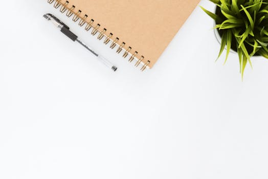 pexels-photo-733852-733852 Minimalist stationery setup with a spiral notebook and pen on a clean white desk.